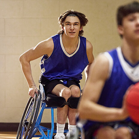 SMA advocate wearing basketball jersey playing wheelchair basketball