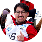 SMA Patient Advocate in wheelchair wearing a racing bib and celebrating with a thumbs up